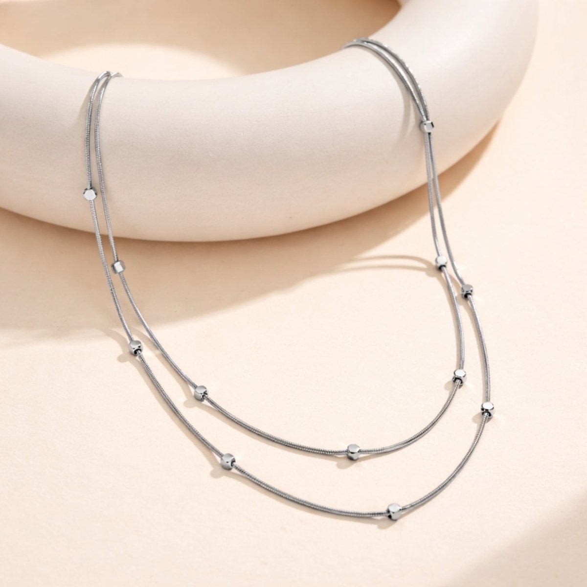 Detailed product information for the Kouvr layered necklace showing its 304 stainless steel material and length specifications.