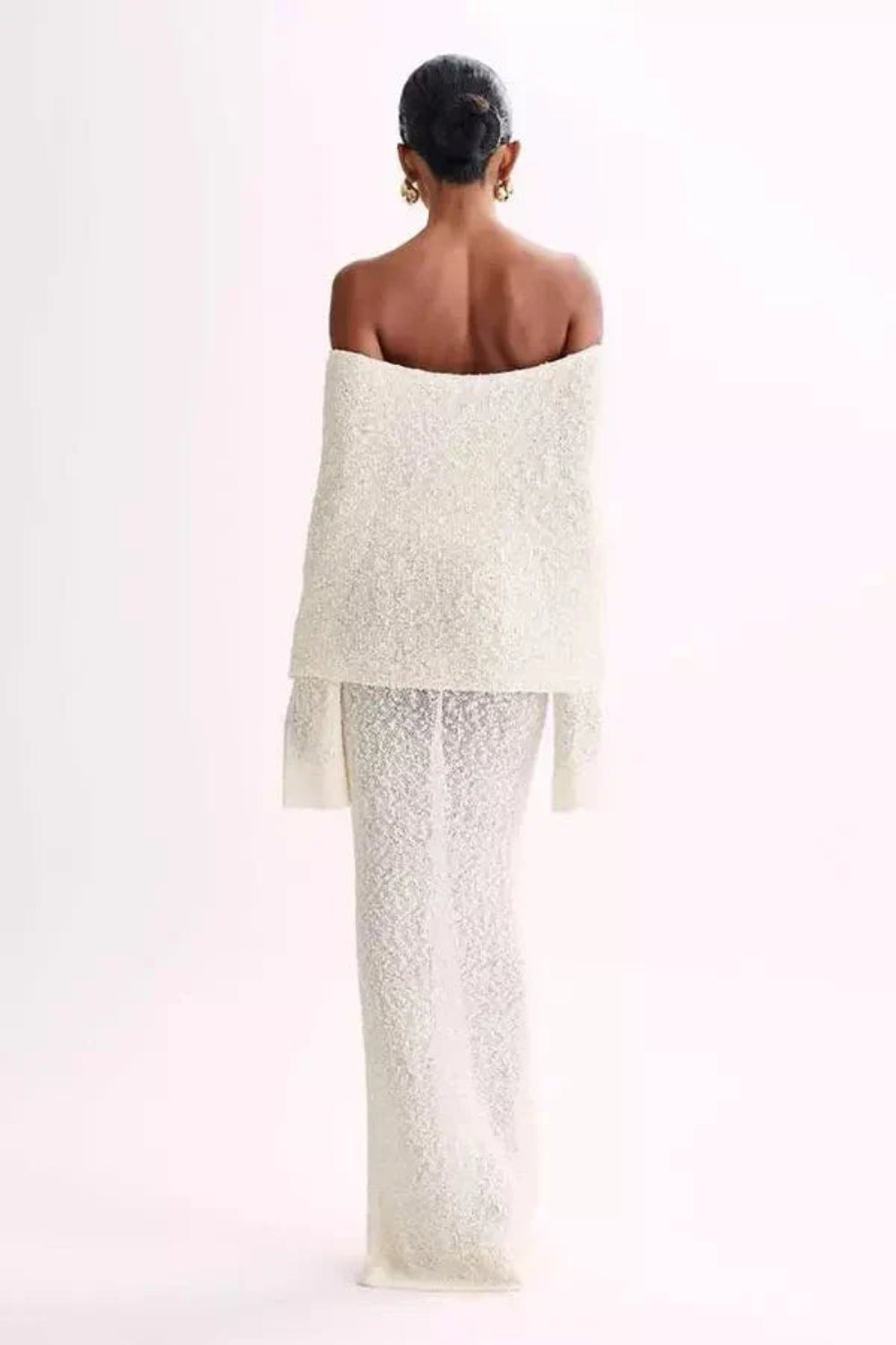 Model wearing Kouvr's ivory off-the-shoulder knit maxi gown, front view