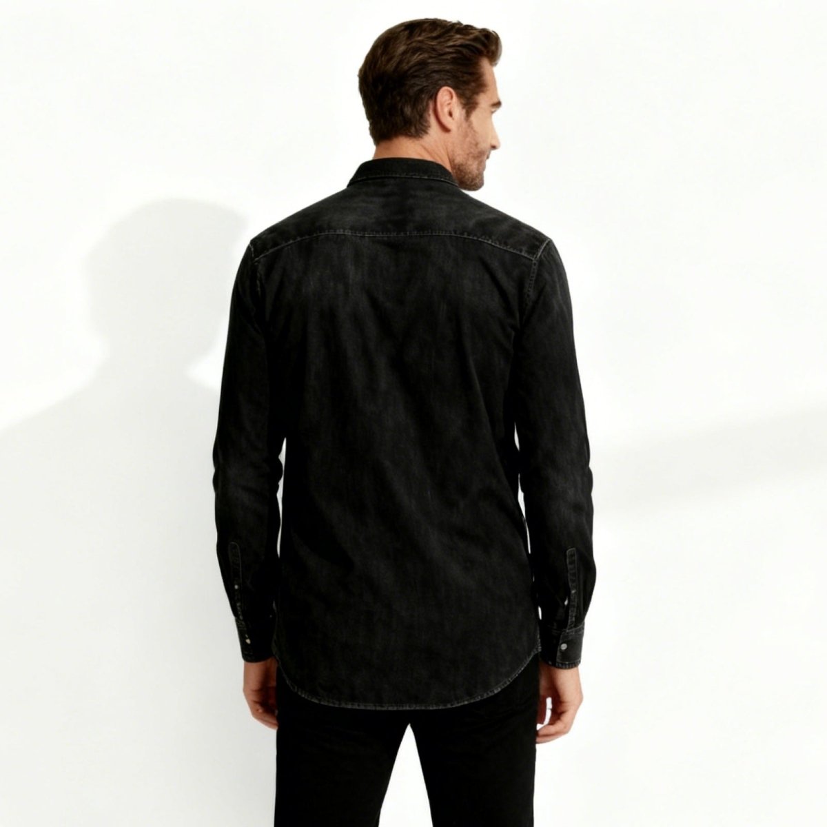 Man wearing a black Kouvr denim shirt on a white background