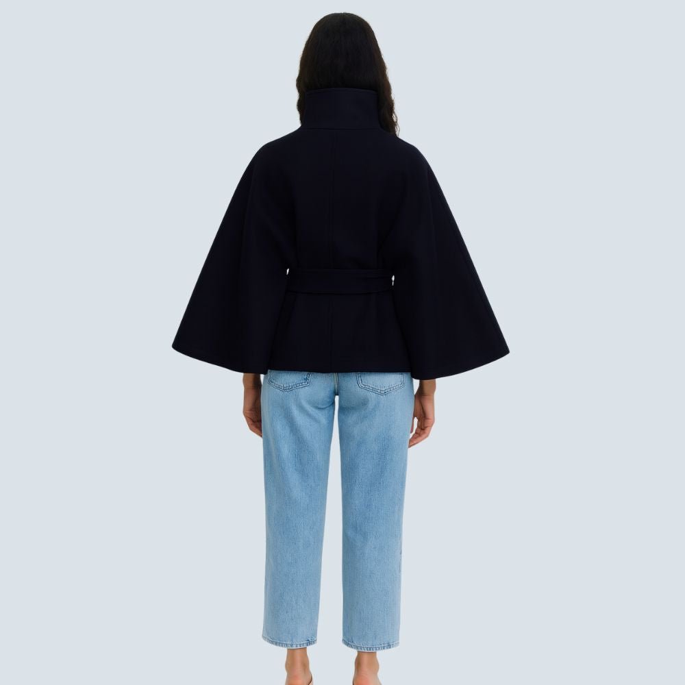 Model wearing the Kouvr Jannah Funnel Neck Wool Cape in Midnight Navy, belted at the waist and paired with light-wash denim