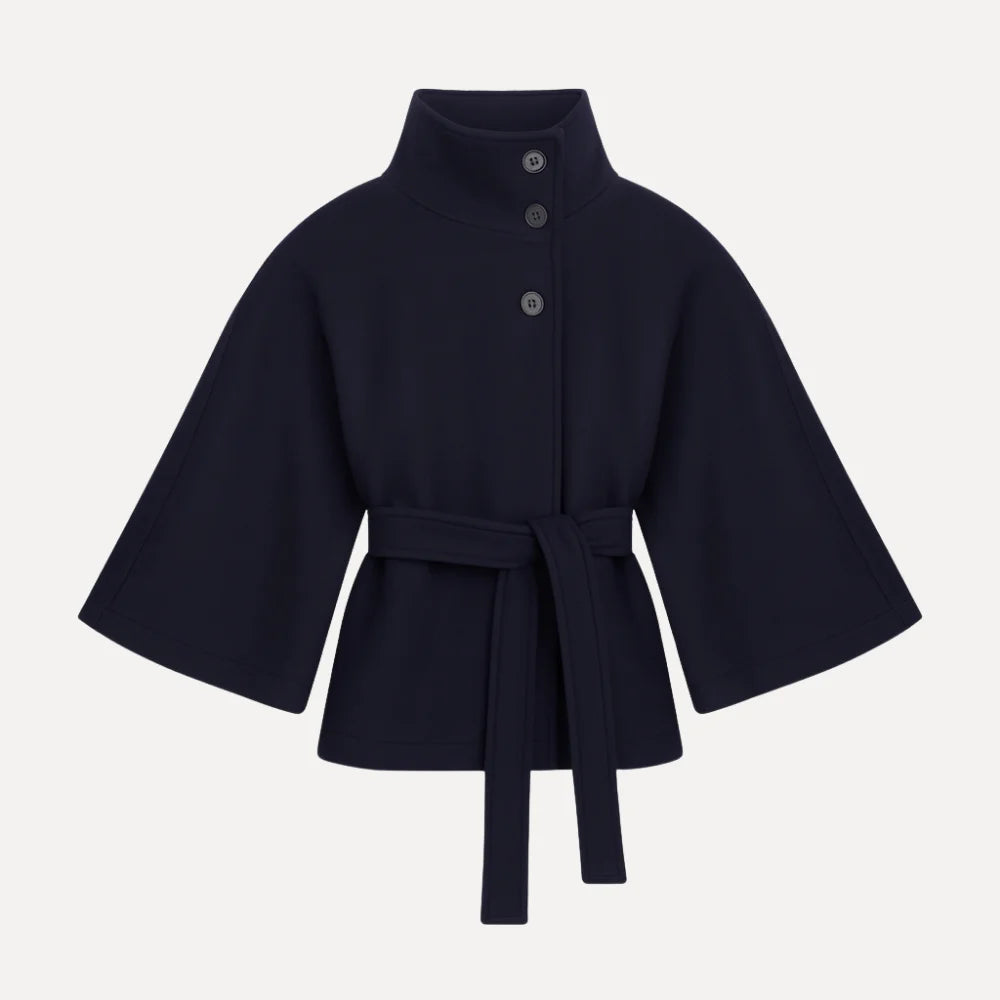 Model wearing the Kouvr Jannah Funnel Neck Wool Cape in Midnight Navy, belted at the waist and paired with light-wash denim