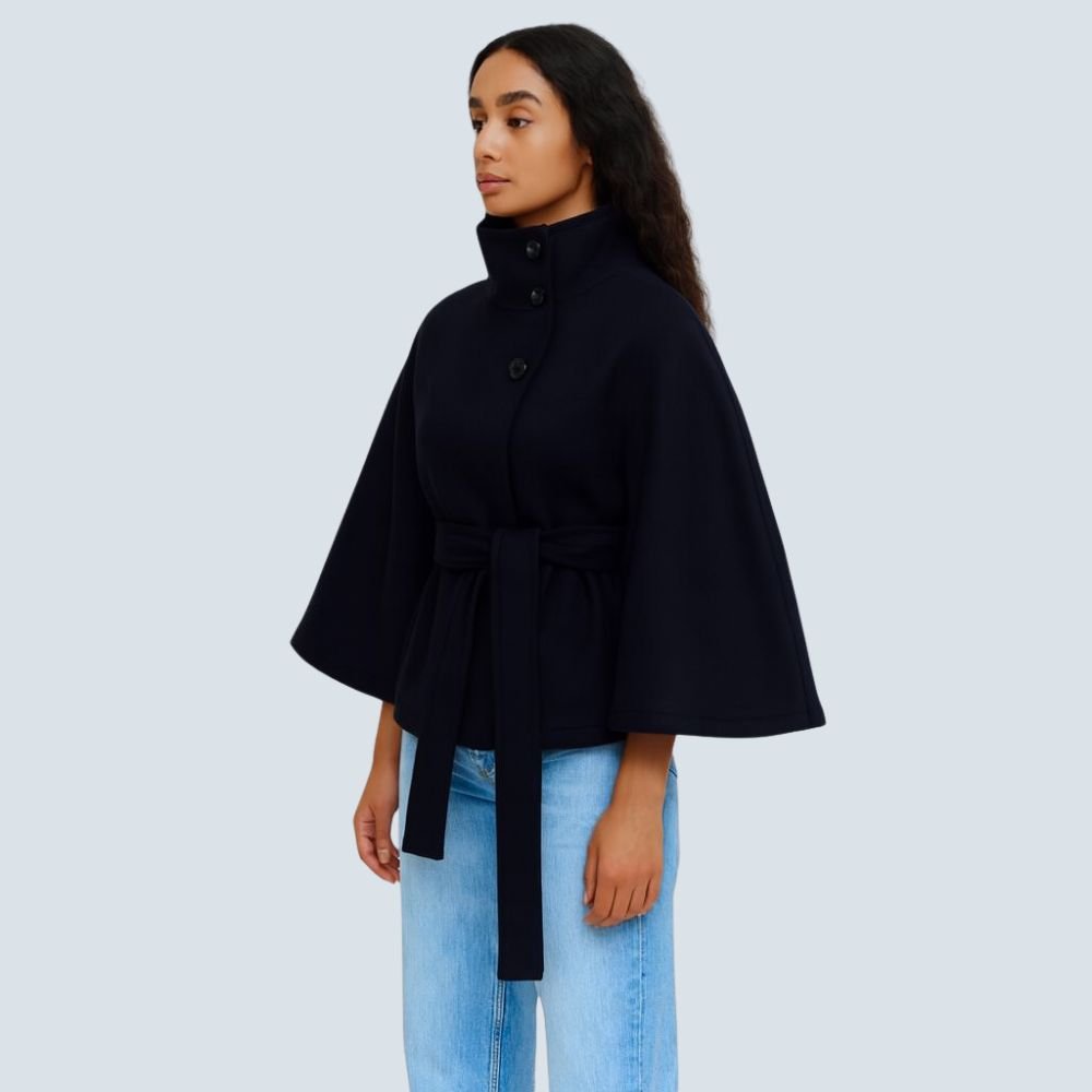Model wearing the Kouvr Jannah Funnel Neck Wool Cape in Midnight Navy, belted at the waist and paired with light-wash denim