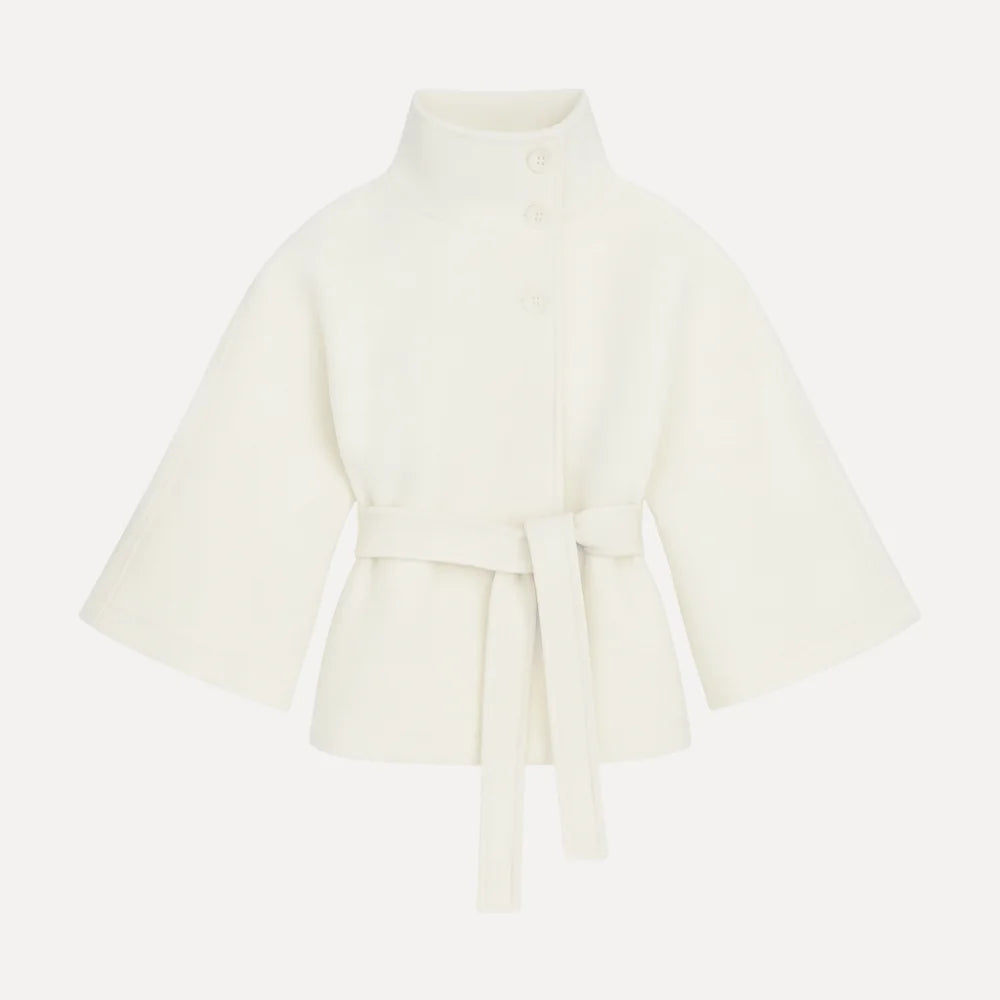 Model wearing the Kouvr Jannah Wool Cape Jacket in White, featuring a high funnel neck and tie-waist belt." For the back view