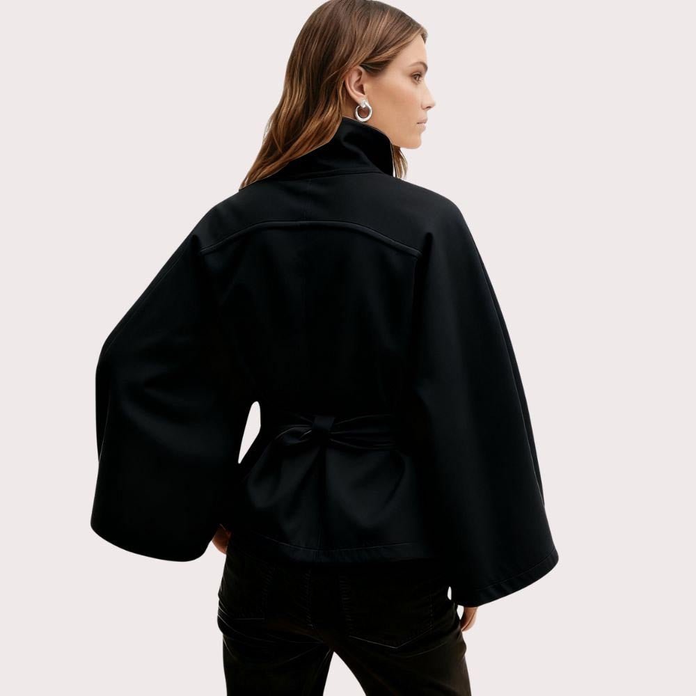 Model wearing Kouvr Fashion belted cape jacket with funnel neck and wide kimono sleeves