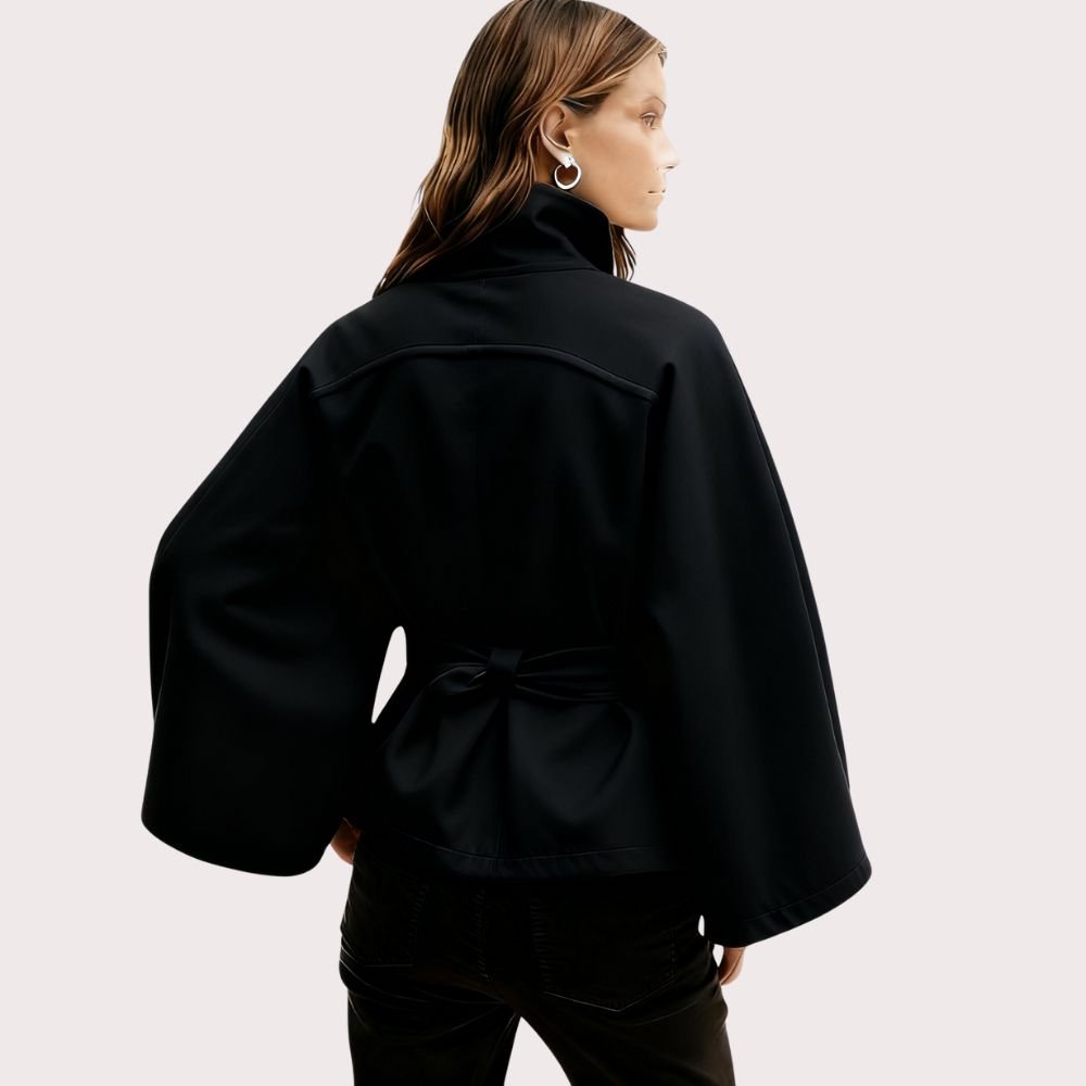 Model from behind wearing the black Kouvr Jaye Cape Jacket, showcasing the tie-back belt and wide kimono sleeves