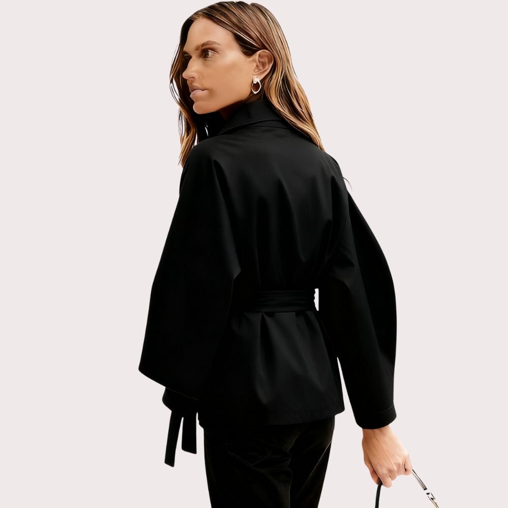 Model from behind wearing the black Kouvr Jaye Cape Jacket, showcasing the tie-back belt and wide kimono sleeves