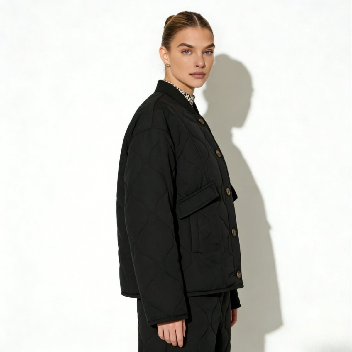 Side profile of a model wearing the Kouvr Jennalyn black collarless quilted jacket, showcasing its relaxed, oversized silhouette and drop shoulders.