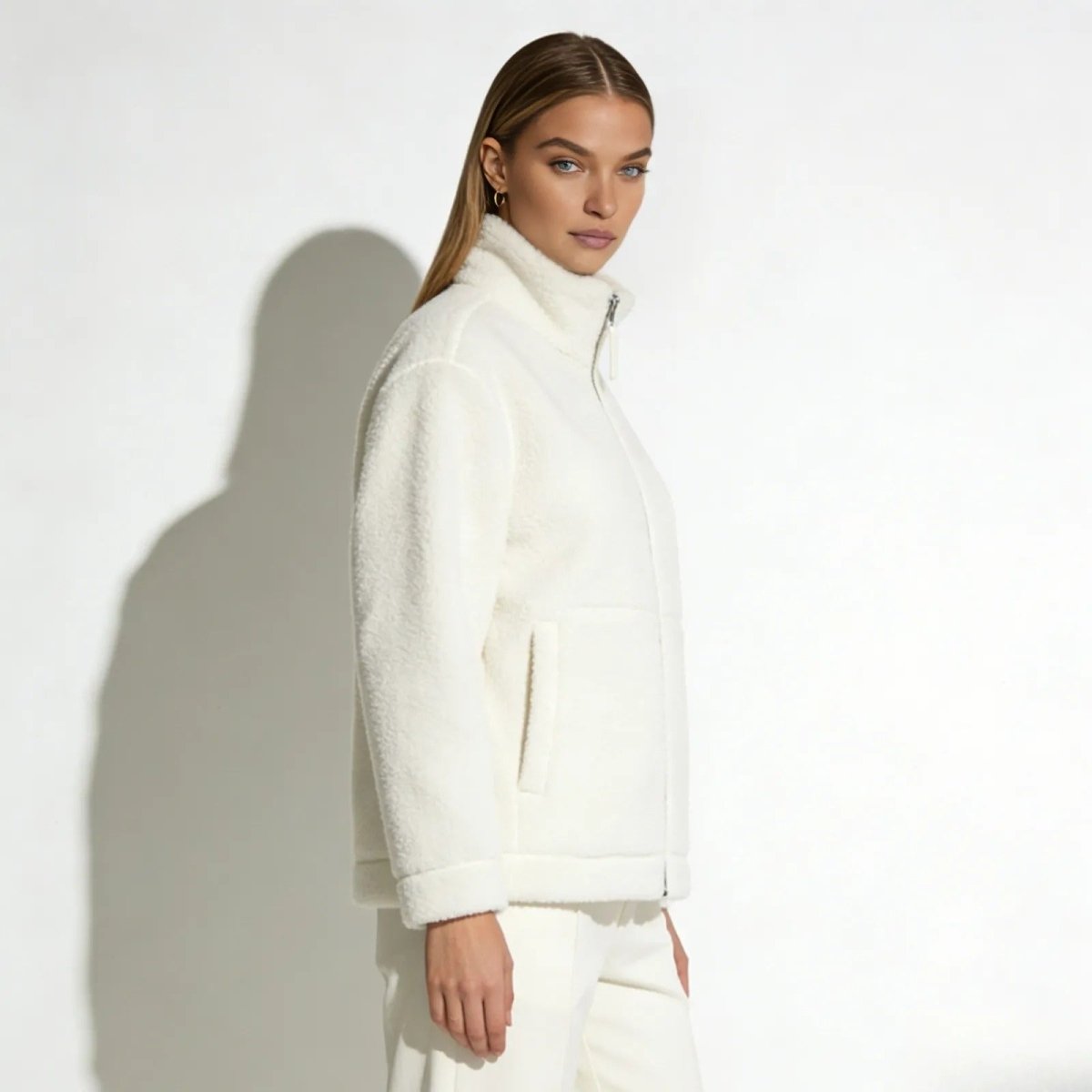 Side profile view of a model in the white Julie high-collar sherpa jacket, showcasing its silhouette and fit.