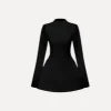 Woman wearing Kouvr Kaisha black long sleeve open-back mini dress in a stone archway