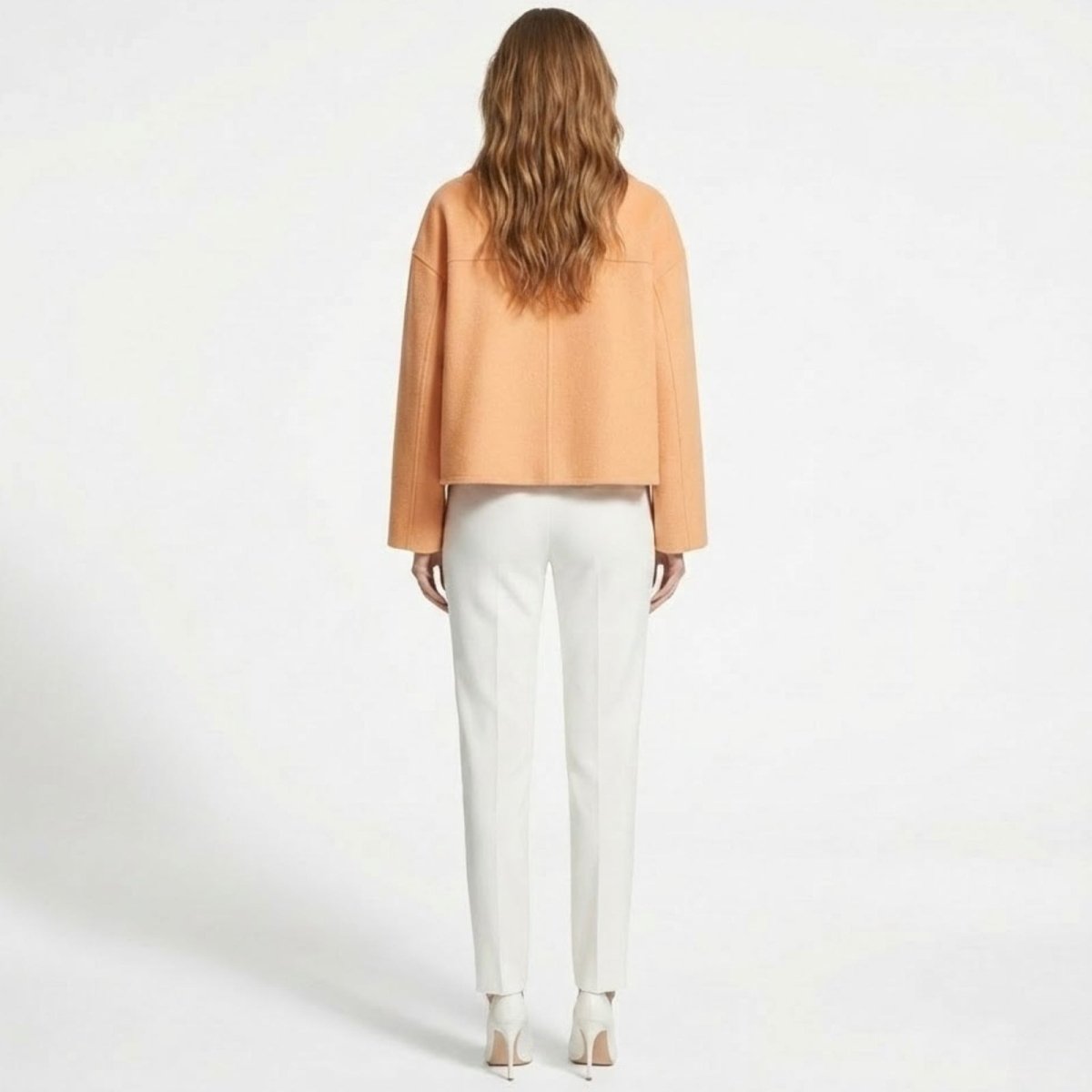 Product flat lay of the double-breasted Kouvr Claudia cropped wool jacket in peach, highlighting the texture of the fabric and button details.