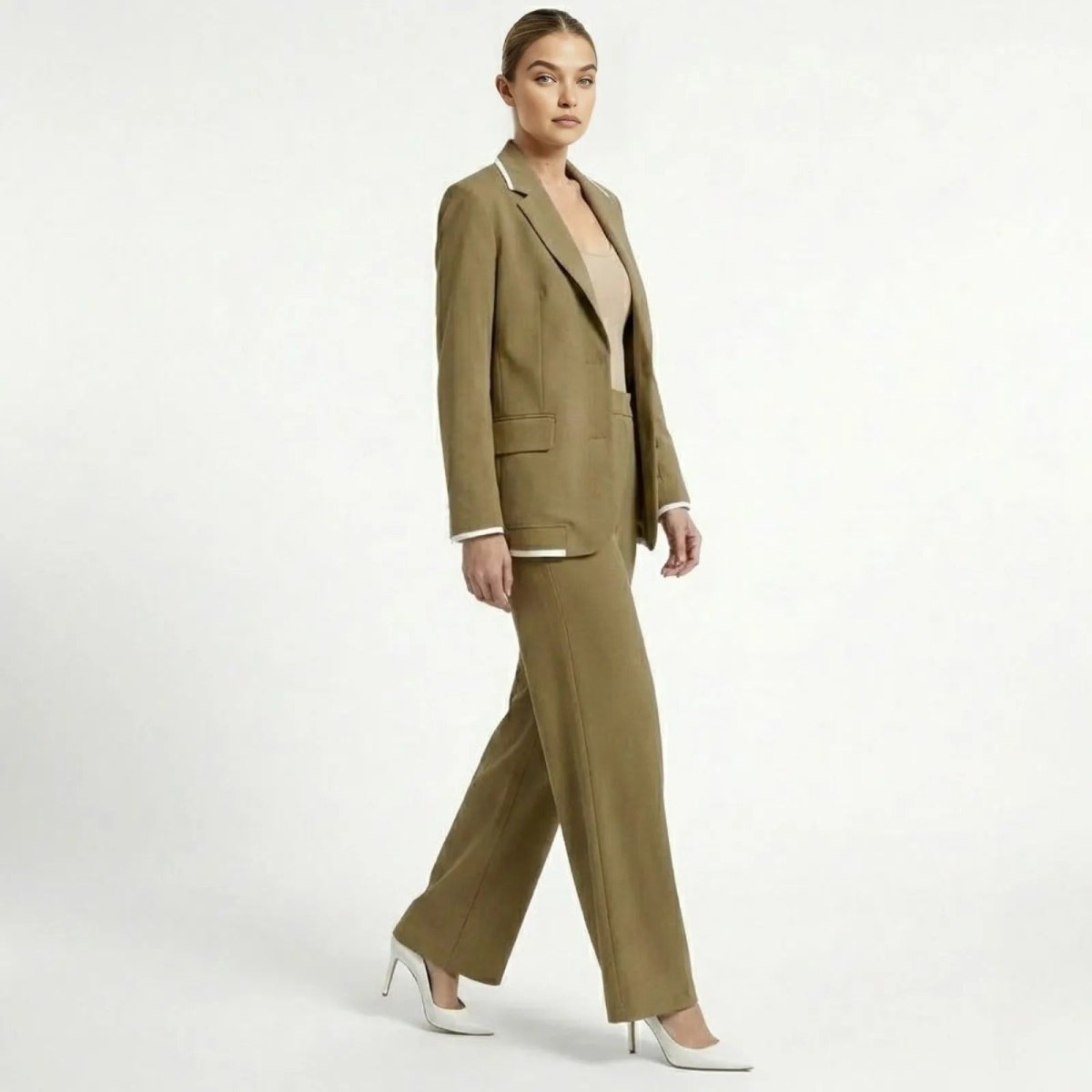 Model in a walking pose wearing the Kouvr khaki suit set and white heels, showing the fluid movement of the wide-leg trousers and blazer's side profile.