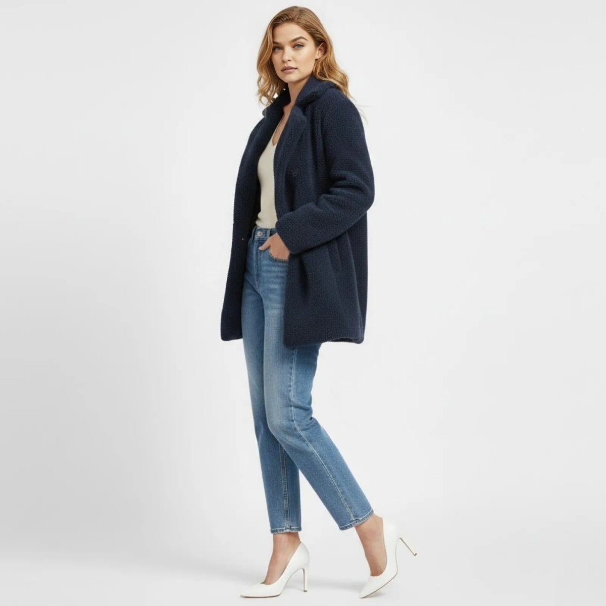 Side profile of a woman in a navy blue sherpa fleece coat, highlighting the relaxed silhouette and elegant drape of the Kouvr Kianna coat.