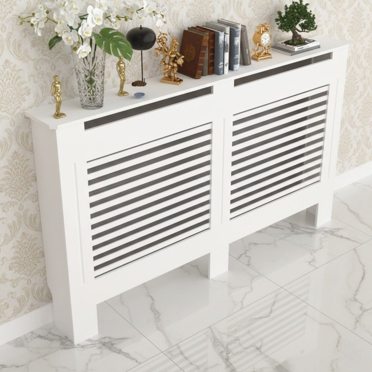 A large white radiator cover with a horizontal slat design, styled with vases, books, and decorative objects in a luxurious hallway with patterned wallpaper.