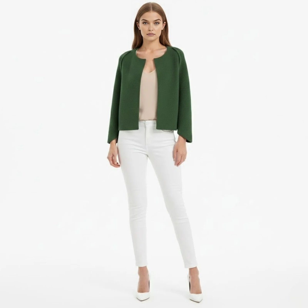 Model wearing the Kouvr Laverne collarless bouclé jacket in Dark green, styled with a cream top, white skinny jeans, and white stiletto heels.