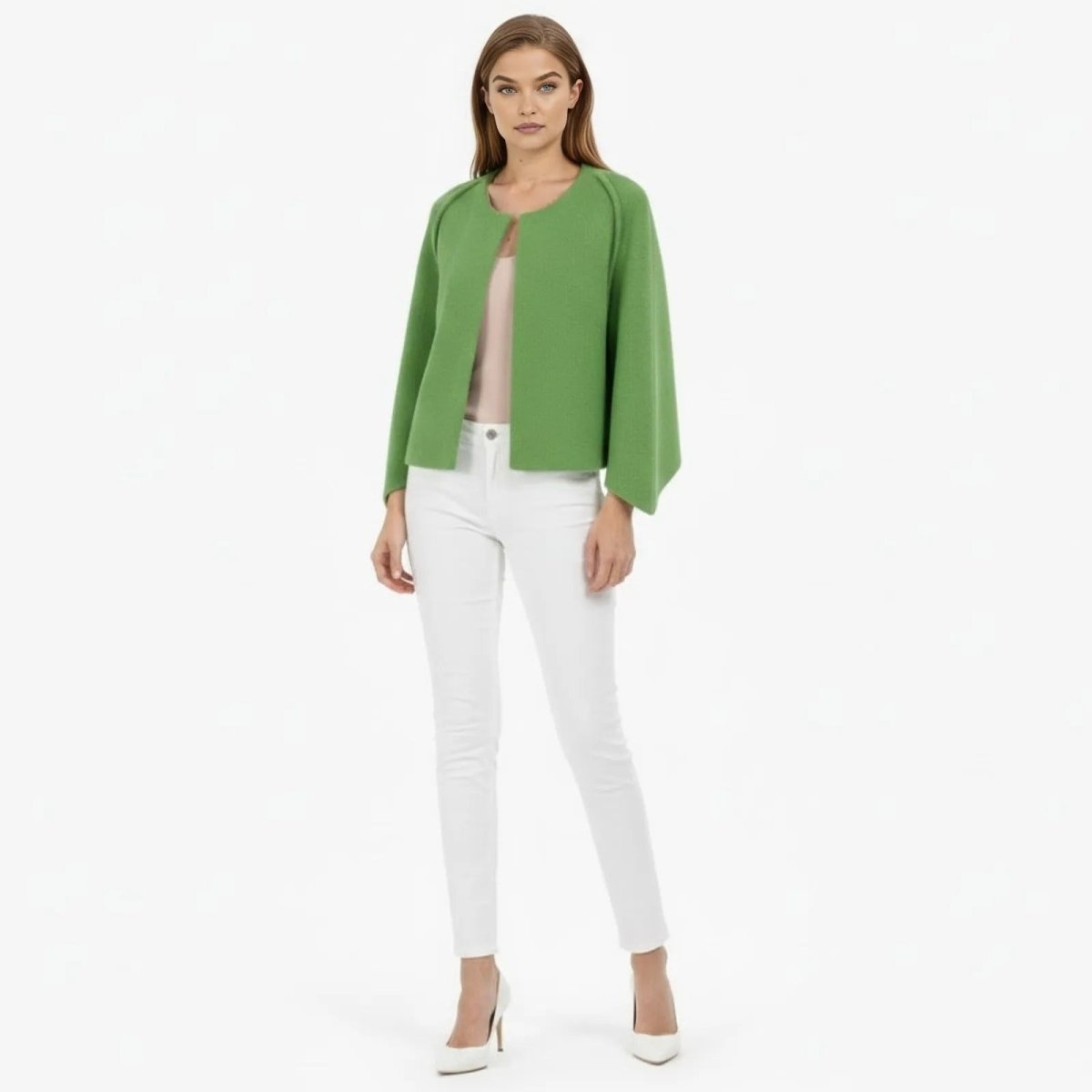 Model facing forward wearing the Kouvr Laverne structured cape jacket in green with a pink top, white jeans, and white heels.