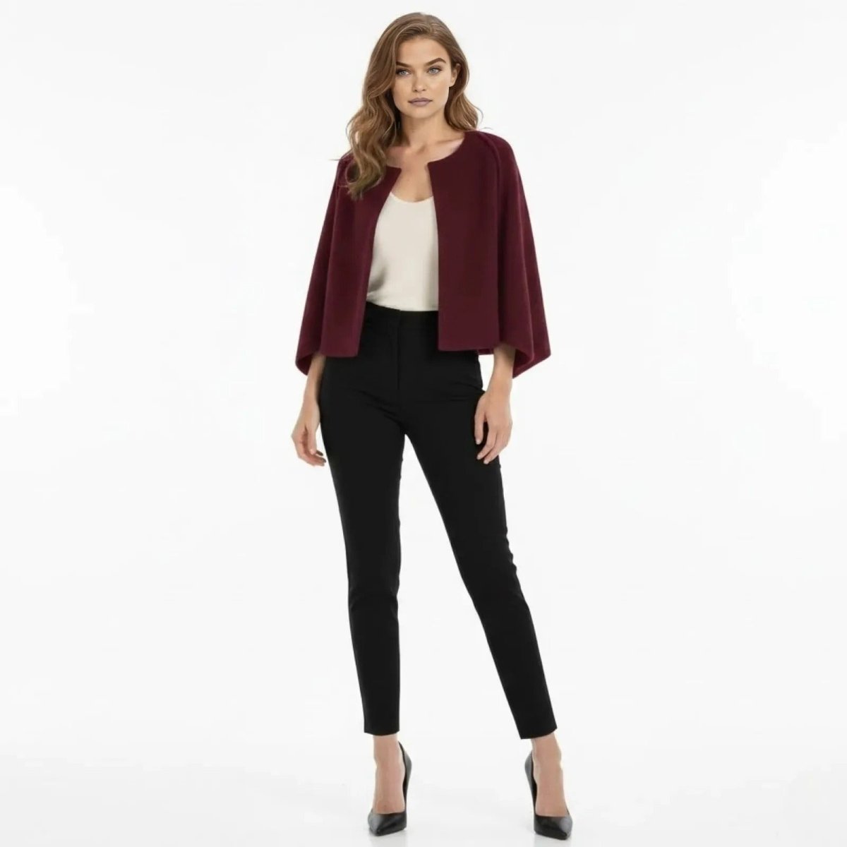 Woman wearing the Kouvr Laverne Structured Capelet in burgundy, styled with black trousers and a white top, front view.