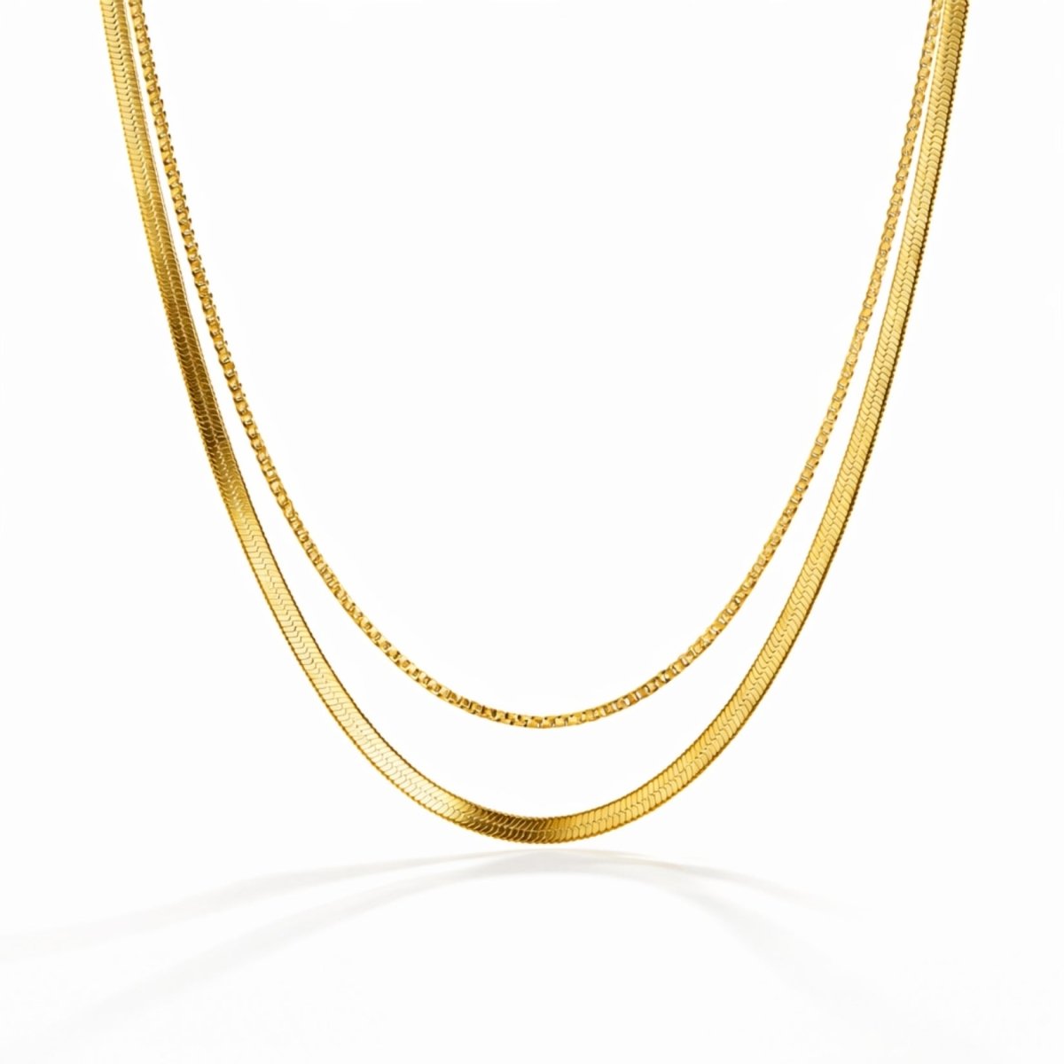 Kouvr layered gold necklace set with a flat snake chain and a thin box chain on a clean white background.