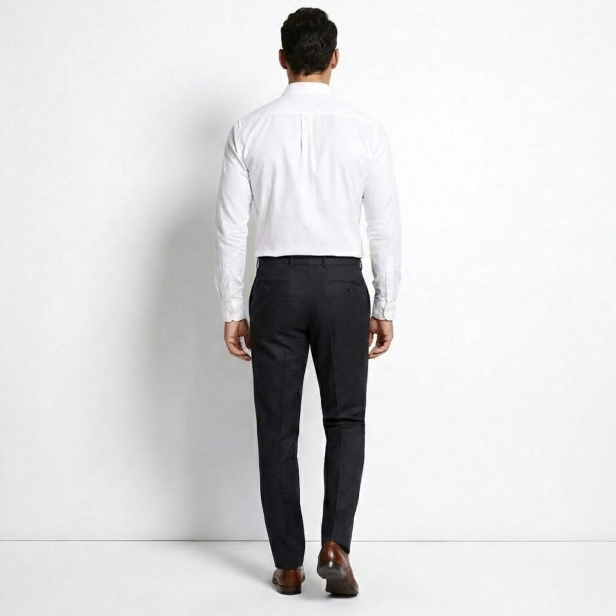 Rear view of a male model wearing the Kouvr Leland White Dress Shirt, highlighting the slim fit and rear darts.
