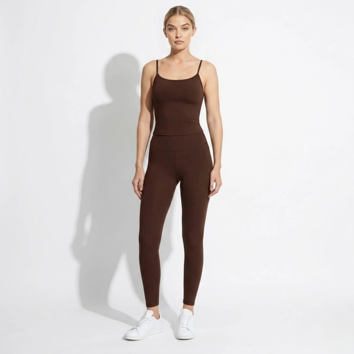 Full body shot of model in Kouvr luxury stretch fitted camisole and brown athletic leggings
