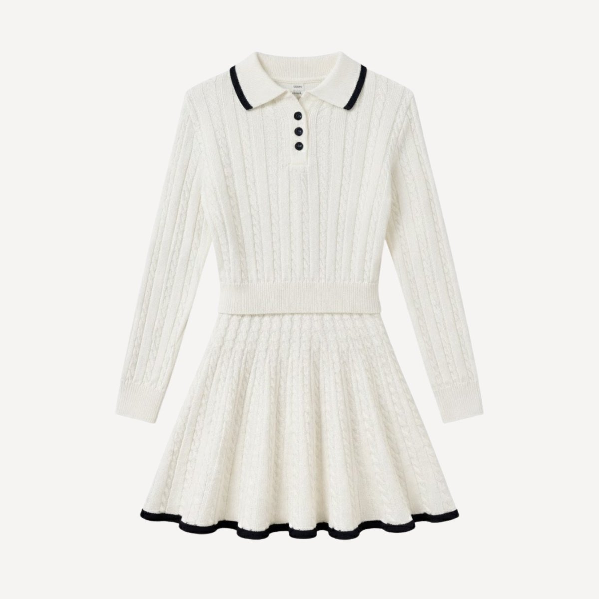 Flat lay of the Maisy two-piece set, displaying the white cable knit polo sweater and pleated mini skirt with black contrast tipping details.