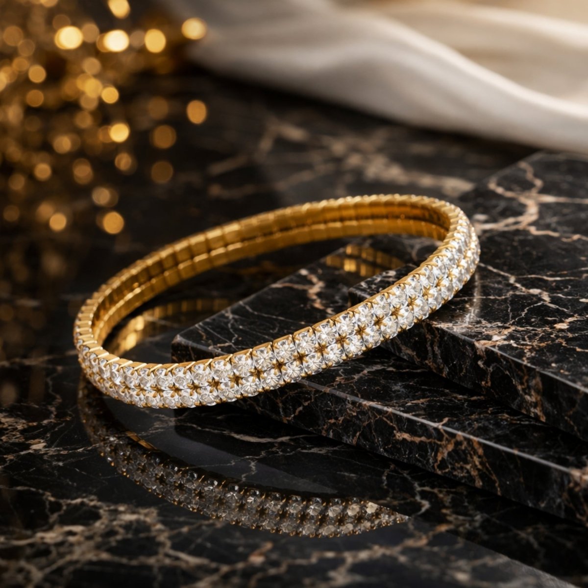 The Kouvr Marzanna  gold stretch tennis bracelet resting on a black marble surface with its reflection visible.
