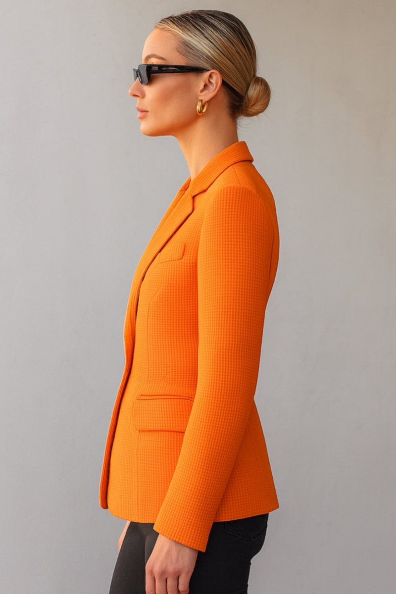 single-breasted tailored jacket," "vibrant orange power blazer," "luxury workwear for women," "statement office jacket," "basket-weave fabric," "impeccable tailoring," "transitional outerwear," "professional women's clothing