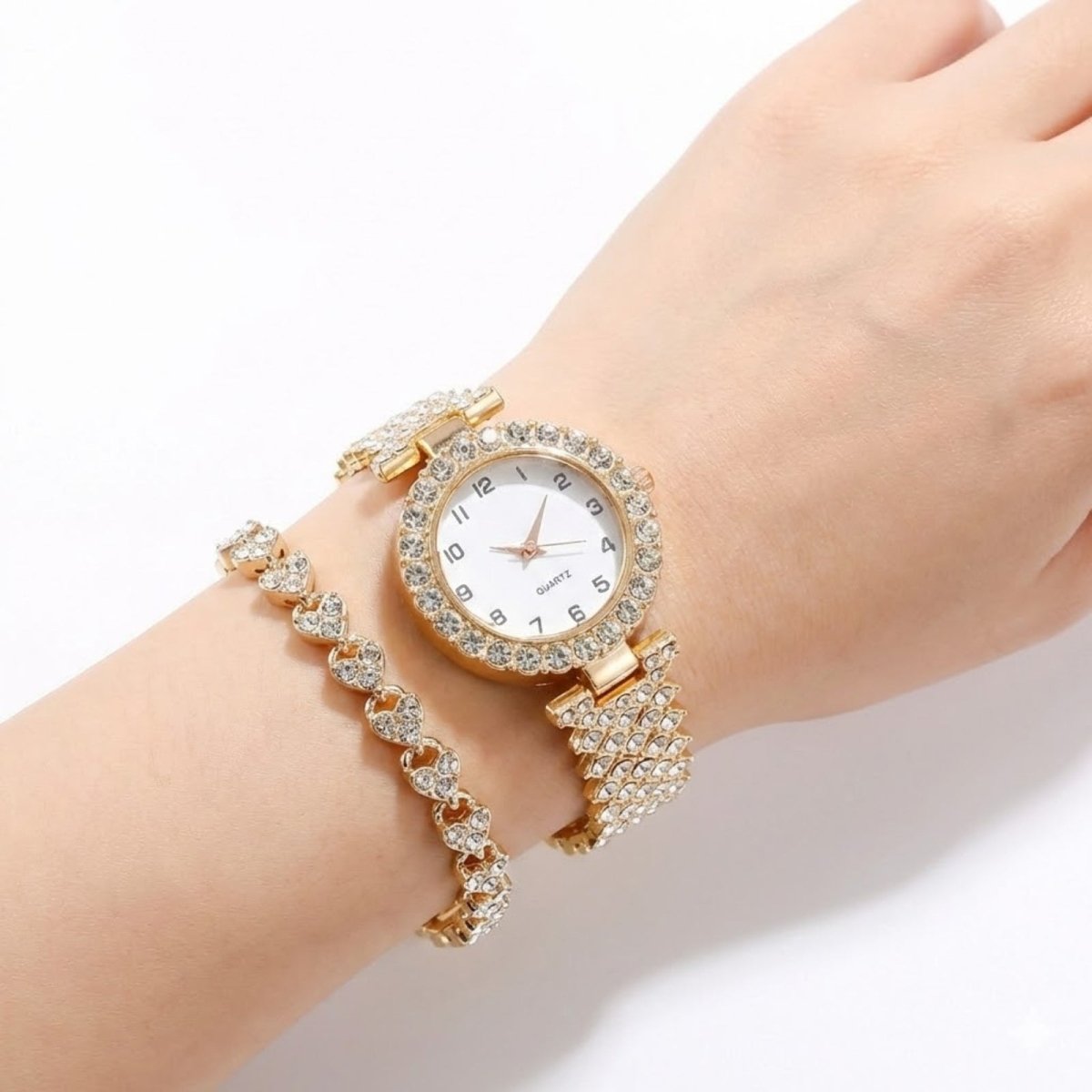A woman's wrist wearing the Kouvr Maya gold crystal watch and heart bracelet, showcasing the elegant fit and sparkle.