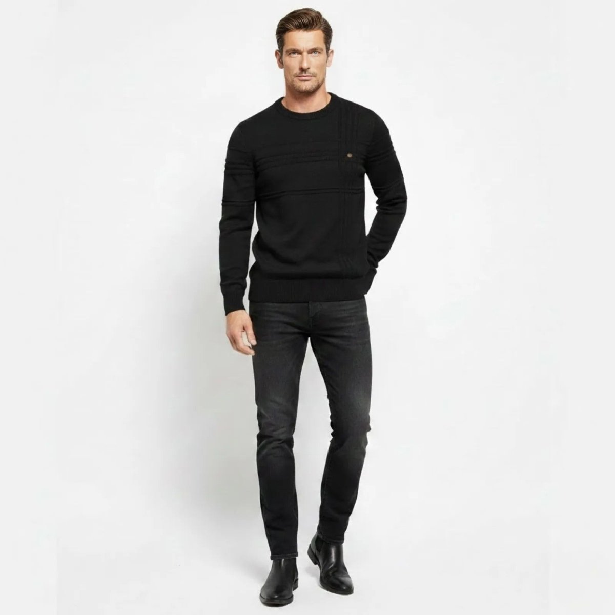 Model wearing the Kouvr men's black textured crewneck sweater with slim fit black jeans, front view.