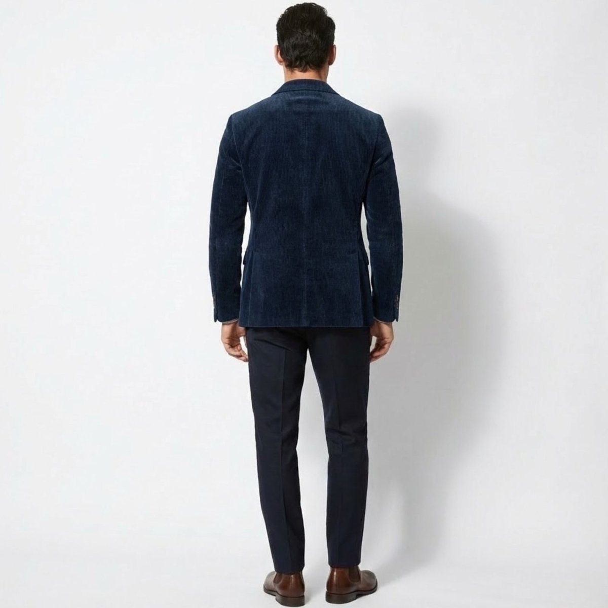 Rear view of the Kouvr men's dark blue corduroy blazer highlighting its tailored construction and fit on a male model.