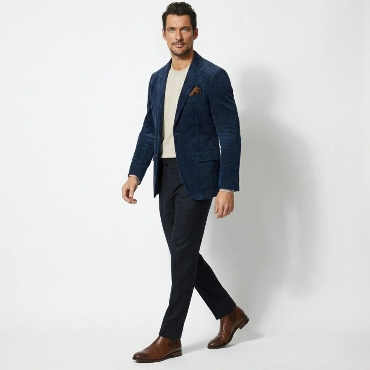 Side profile of a man walking while wearing a Kouvr slim fit dark blue corduroy sport coat, showcasing its excellent fit and natural drape.
