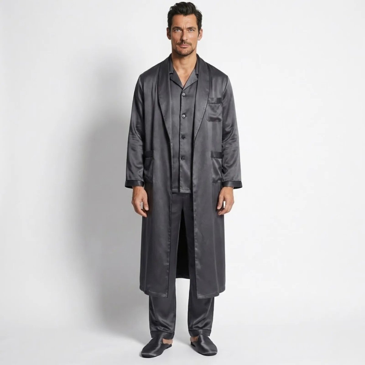 Male model wearing the complete Kouvr three-piece dark grey satin lounge set, including the open long robe, buttoned pajama shirt, and trousers, facing forward.