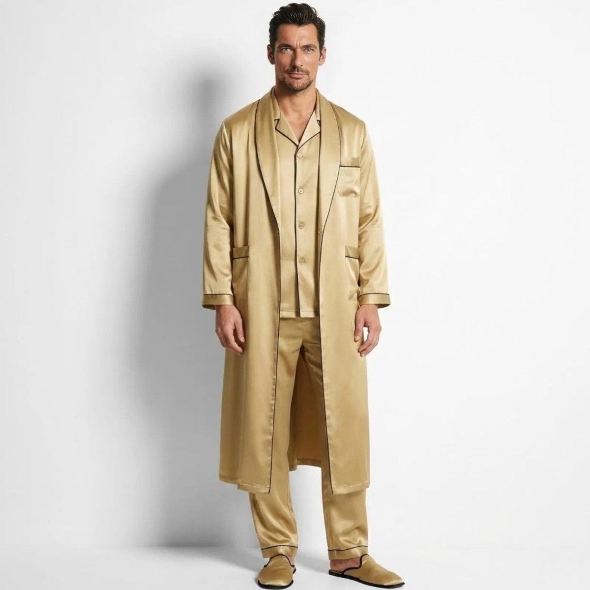 Male model wearing the Kouvr three-piece gold satin pajama set with a matching long robe, viewed from the front against a white background.