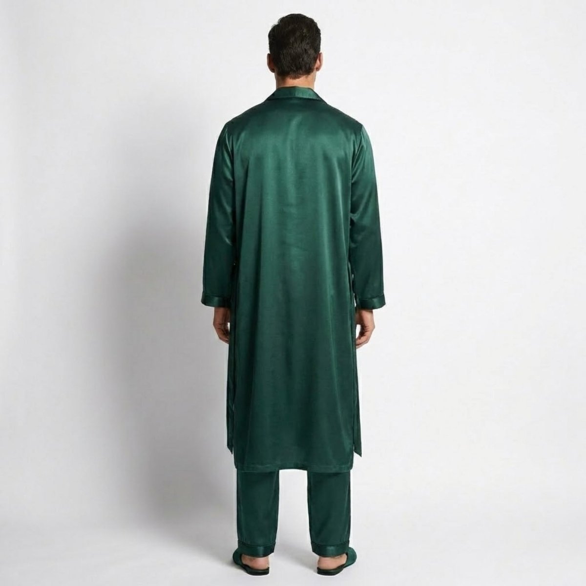 Back view of a male model wearing an green satin robe and pajama set, displaying the fit and flow of the fabric.
