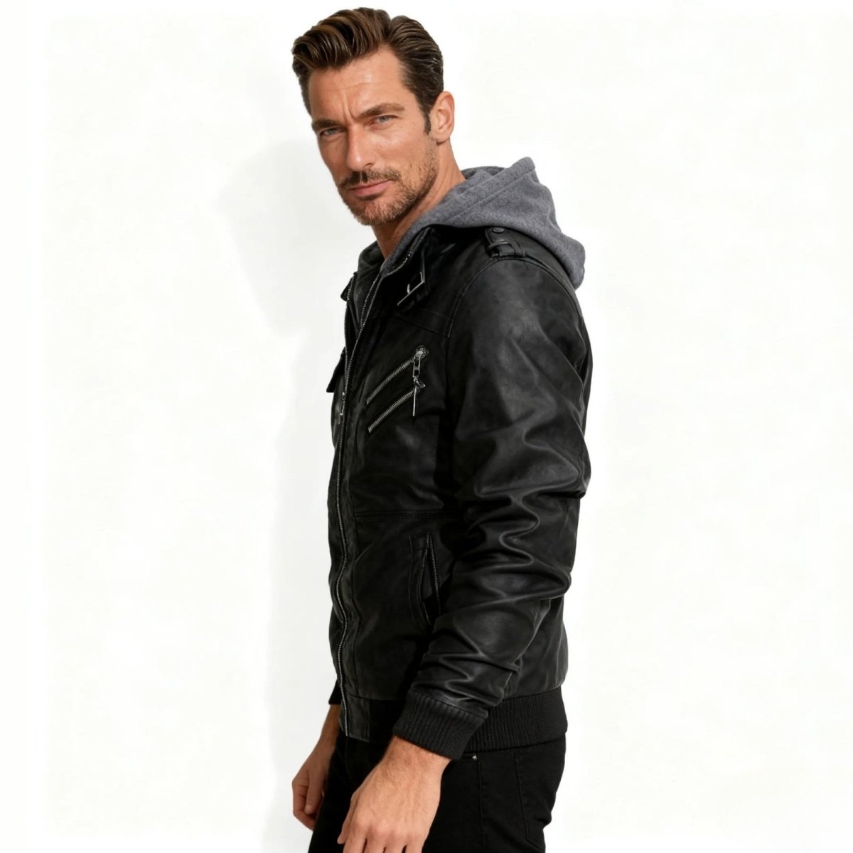 Side profile of a man wearing the black Kouvr biker jacket with a grey removable hood, showing the slim fit.
