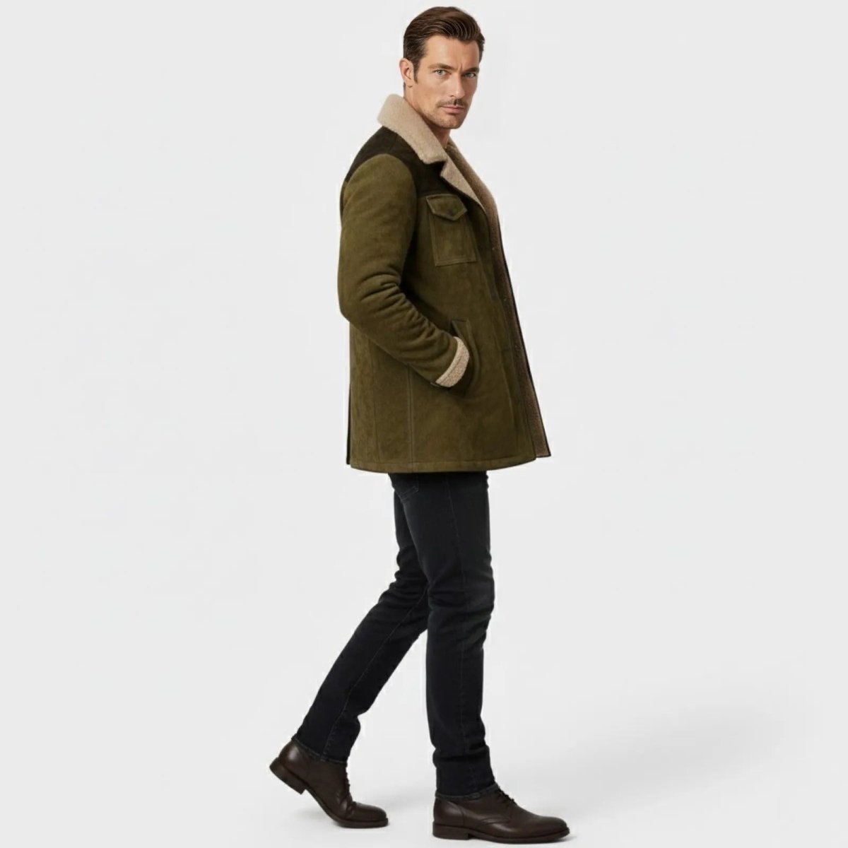 Side profile of a male model walking in the Kouvr olive suede jacket showcasing its fit and sherpa collar.
