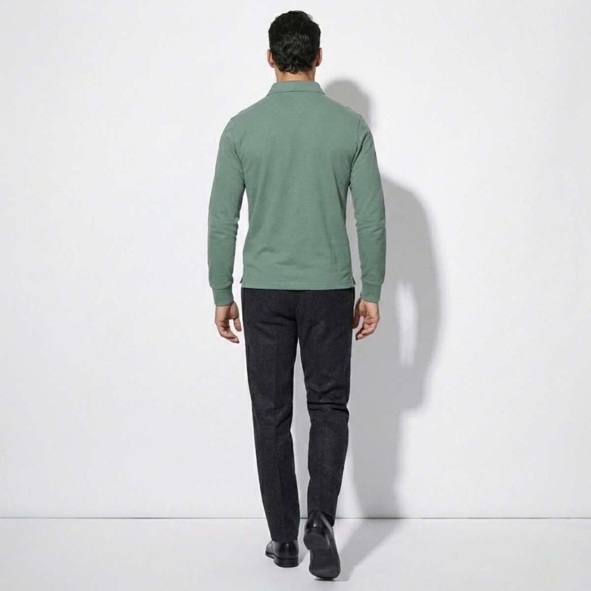 Back view of model wearing the Kouvr sage green long sleeve polo shirt, highlighting the clean lines and tailored fit.
