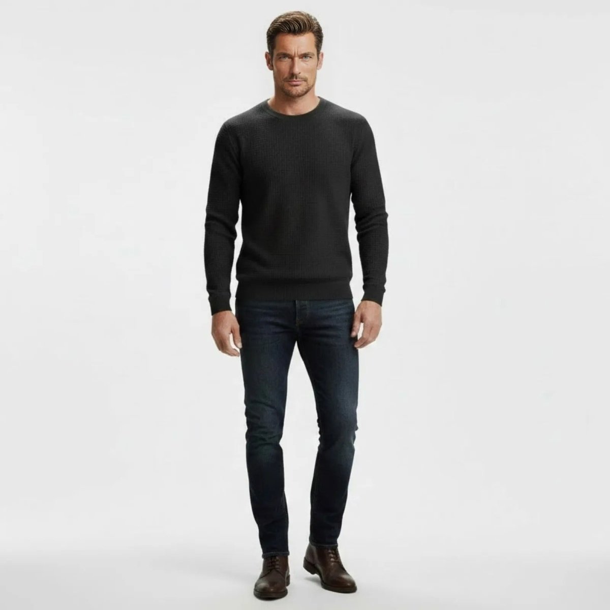 Male model wearing the Kouvr men's slim fit black waffle-knit crewneck sweater with dark wash jeans, facing forward.