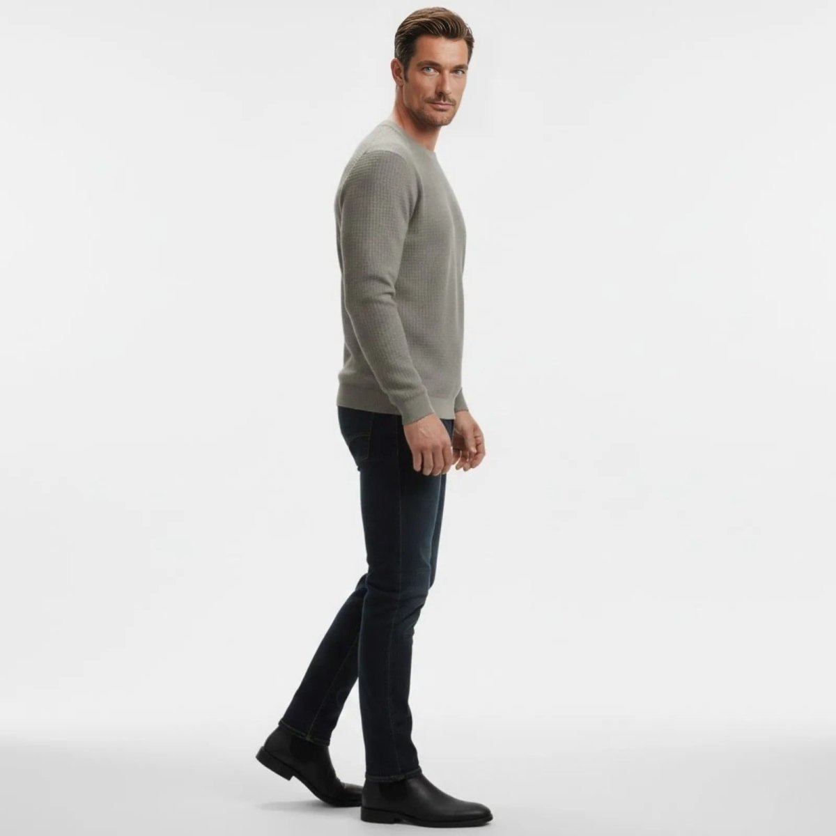 Male model in a side profile view walking while wearing the Kouvr grey textured waffle knit sweater, showcasing its slim fit.