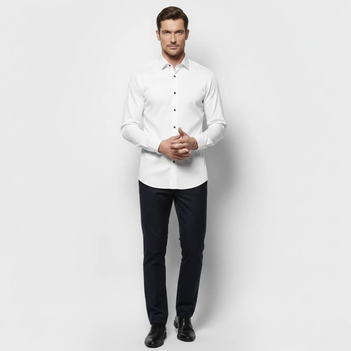 Male model wearing the Kouvr Fashion white slim fit long sleeve dress shirt with black contrast buttons, shown from the front against a white background.