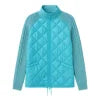 Model wearing the Kouvr Mika Hybrid Bomber Jacket in Aegean Teal, featuring cable-knit sleeves and a diamond-quilted body, paired with light-wash skinny jeans and white sneakers