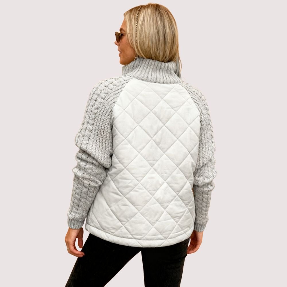 Model wearing the Kouvr Mika hybrid jacket in Heather Gray and Winter White, featuring quilted body and honeycomb knit sleeves, styled with black jeans and sunglasses