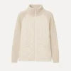 Woman wearing the Kouvr Mika khaki quilted jacket with cable knit sleeves, styled with black jeans