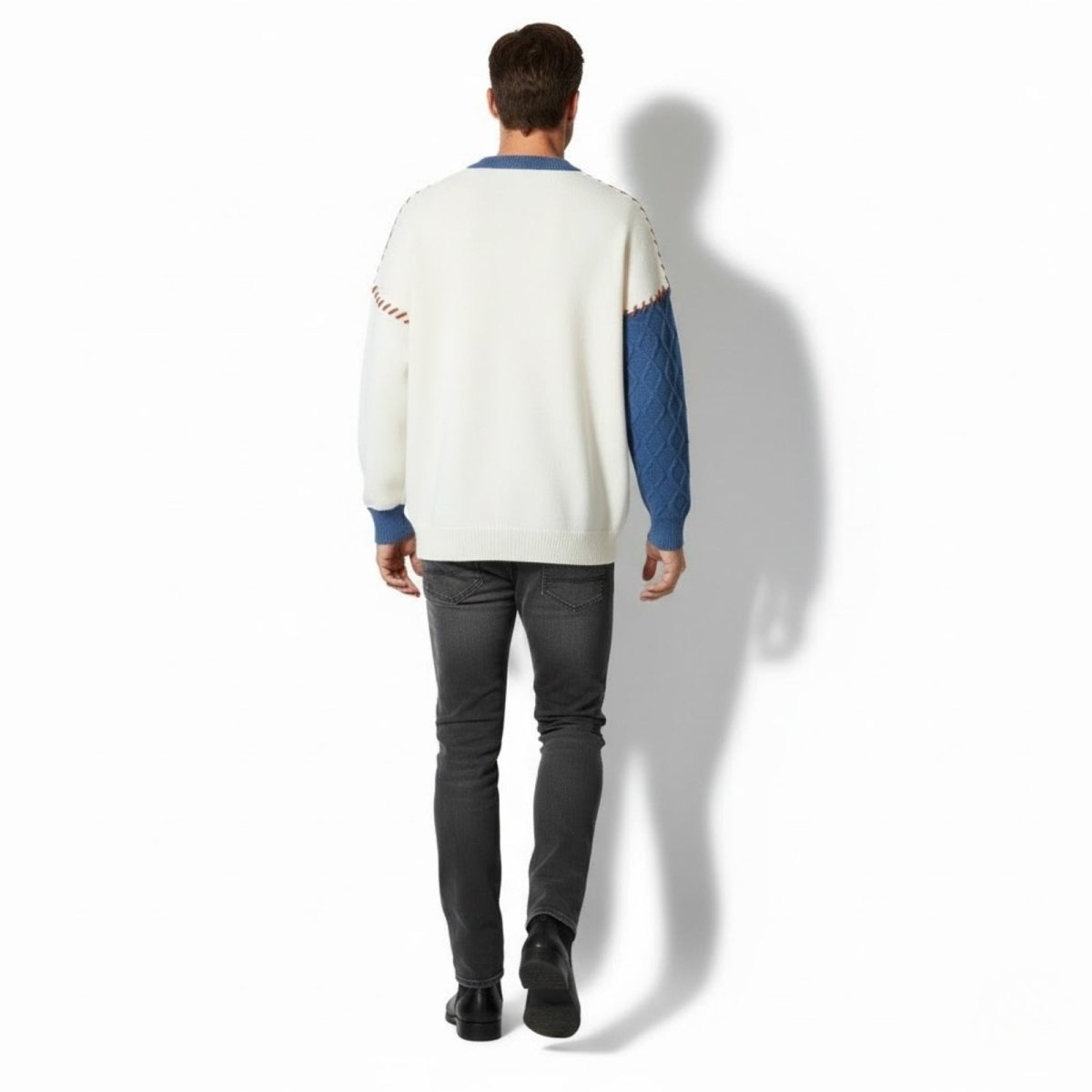 Back view of a male model wearing the Kouvr sweater, highlighting the blue diamond knit sleeve and the cream-colored back panel.