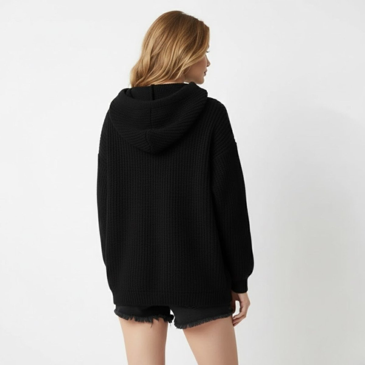 Back view of the Kouvr Nadya oversized black knit hoodie, displaying the generous hood and clean, seamless ribbed knit design.