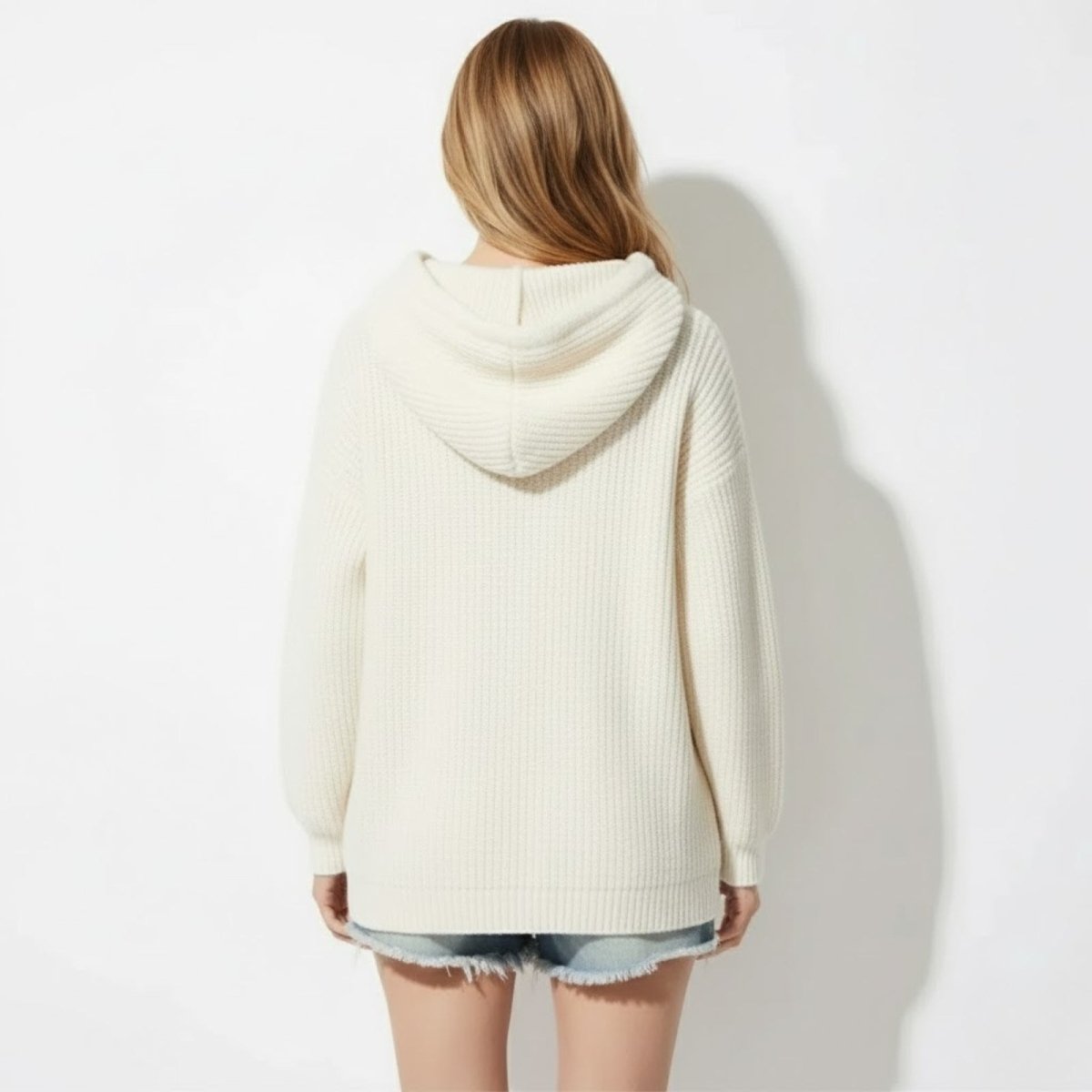Back view of the Kouvr Nadya oversized off  white knit hoodie highlighting the generous hood and ribbed texture.