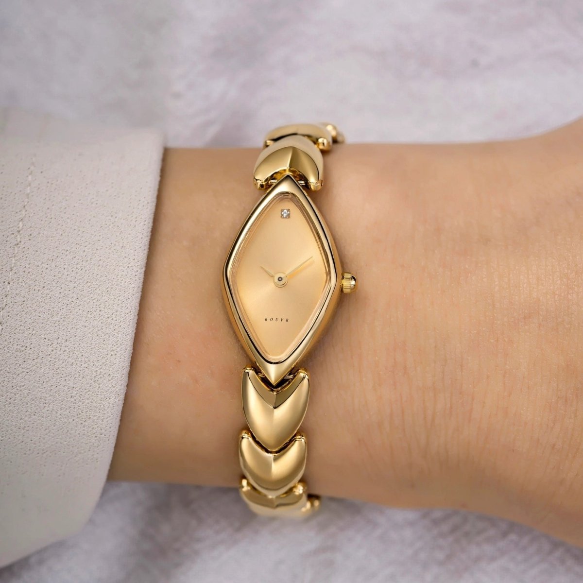 Gold Kouvr watch on a wrist with a light background