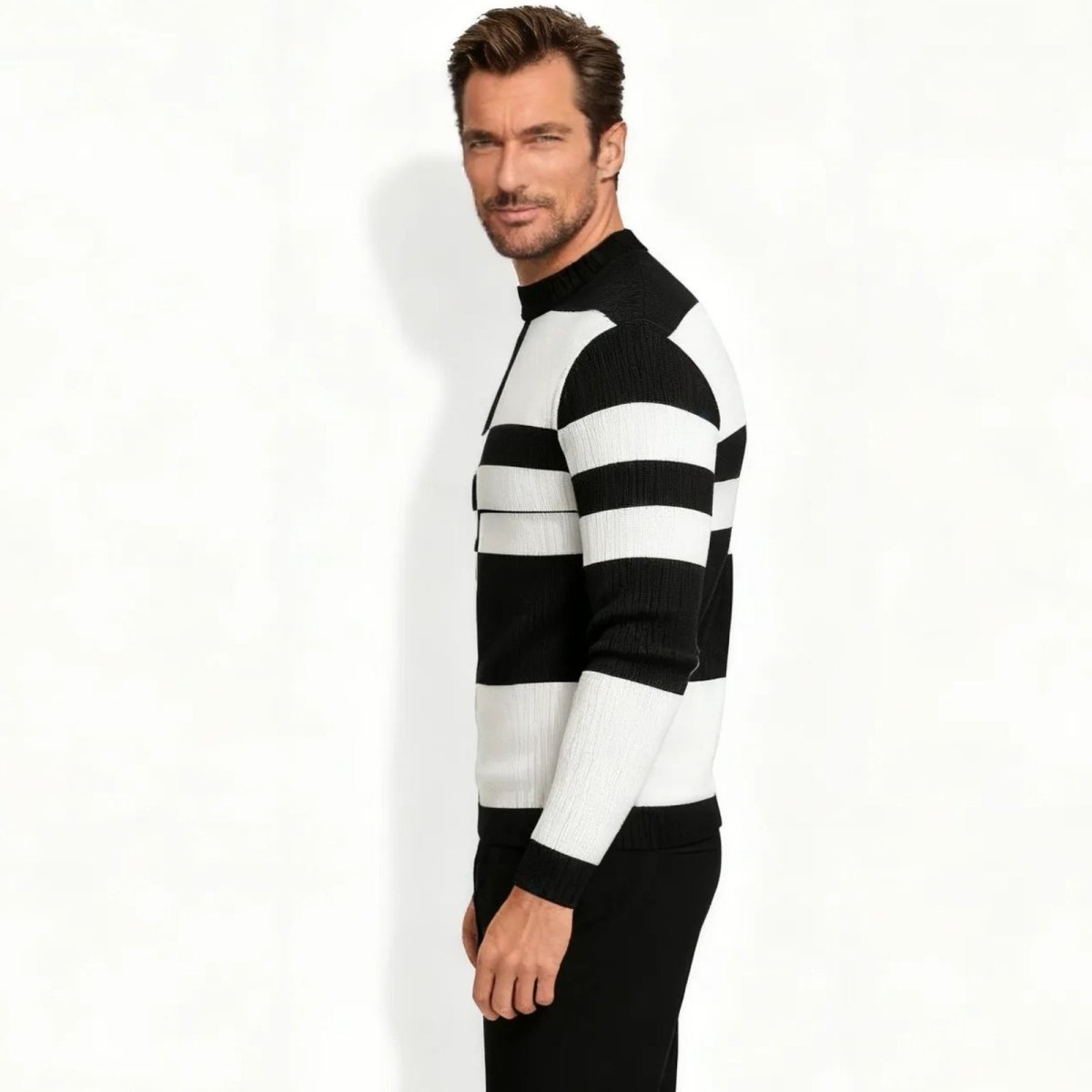 Side profile of a male model in the Kouvr Nerthus black and white ribbed sweater, showing the horizontal stripe pattern on the sleeve.