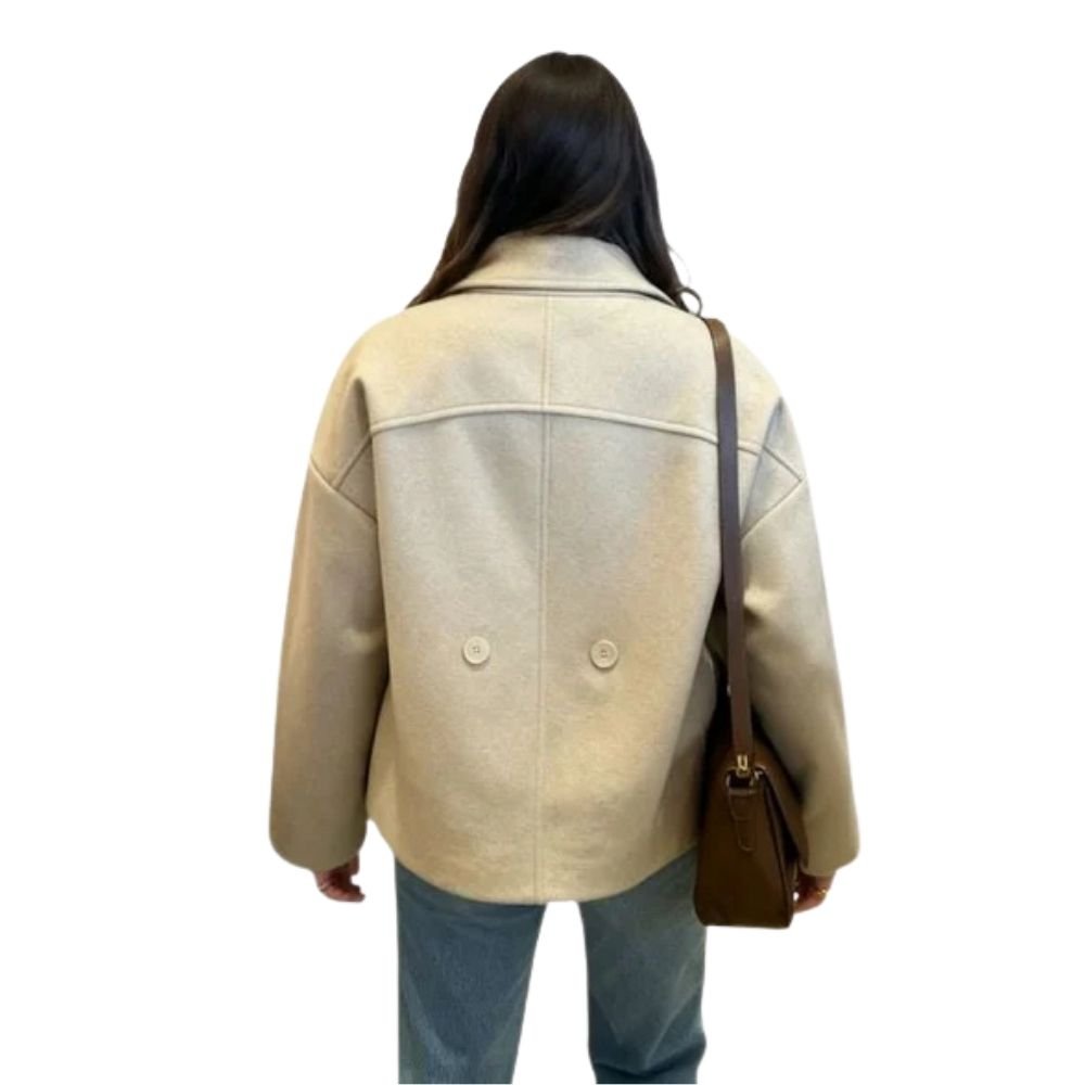 Model wearing the Kouvr oversized oatmeal wool jacket with blue jeans and a brown shoulder bag