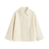 Model wearing the Niana short coat in ivory, styled with a white turtleneck and brown shoulder bag