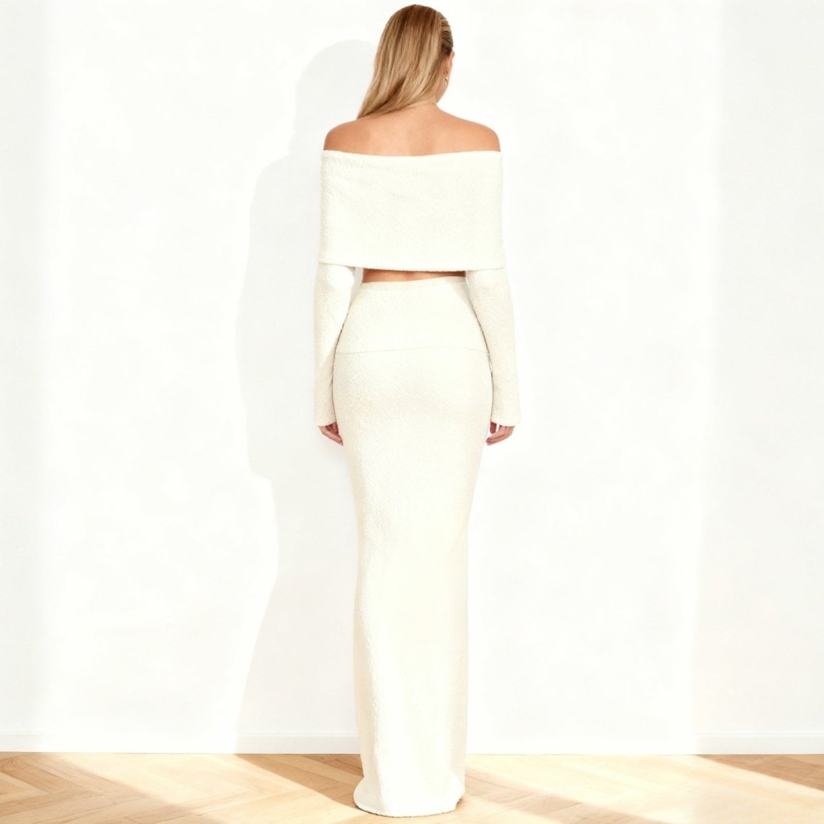 Woman wearing a white Kouvr off-shoulder top and skirt set on a plain background
